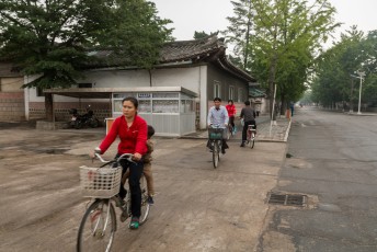 De mensen fietsen, lopen en bussen voorbij in de DPRK met een gezicht alsof er zojuist een dierbare is overleden.